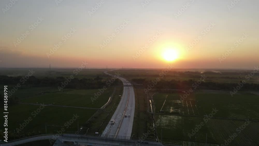 drone away from the highway looking at the horizon at sunset