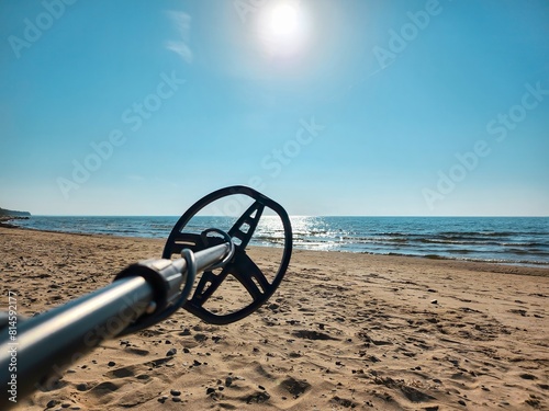 Tranquil and mesmerizing view of a modern metal detector on the sandy beach, creating an inviting atmosphere for an exhilarating treasure hunting experience by the vast blue sea and clear sky.