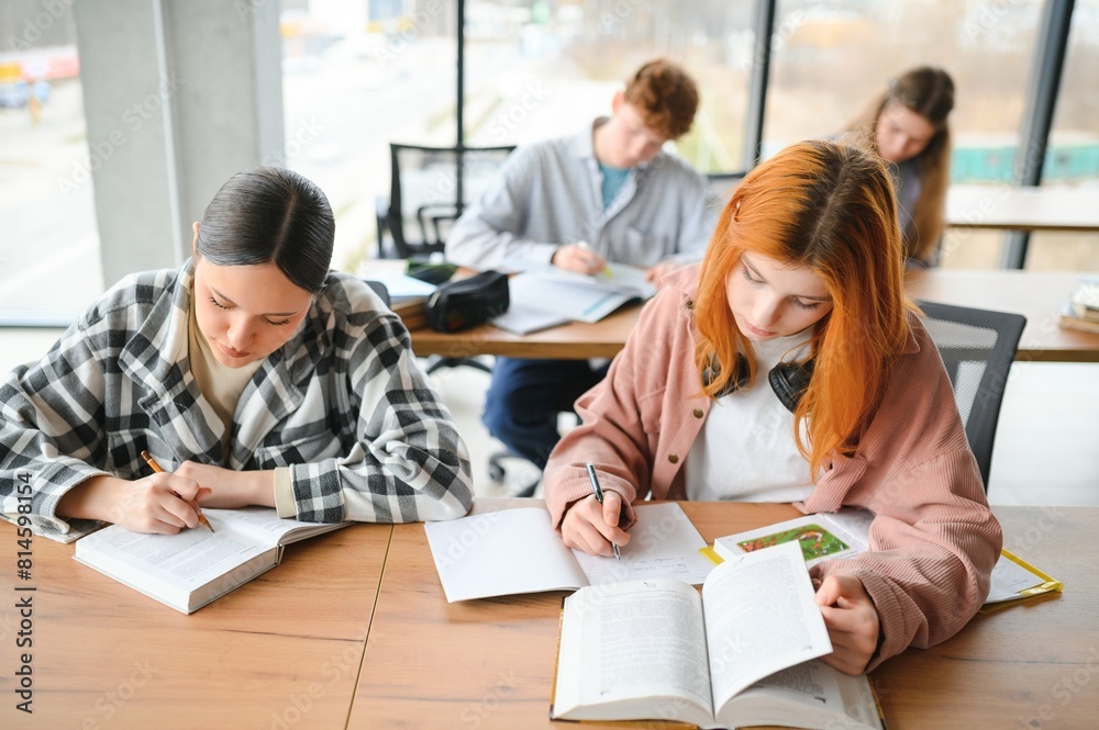 Fototapeta premium students sit at shared desk making notes studying together at university