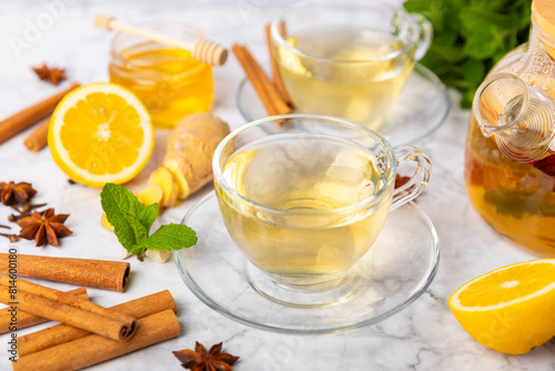 Fragrant hot tea with cinnamon stick and anise on a textured wooden background. A cup of hot tea with honey, lemon, mint and apples. Spicy tea with spices. Immunity tea. Health concept.Copy space.