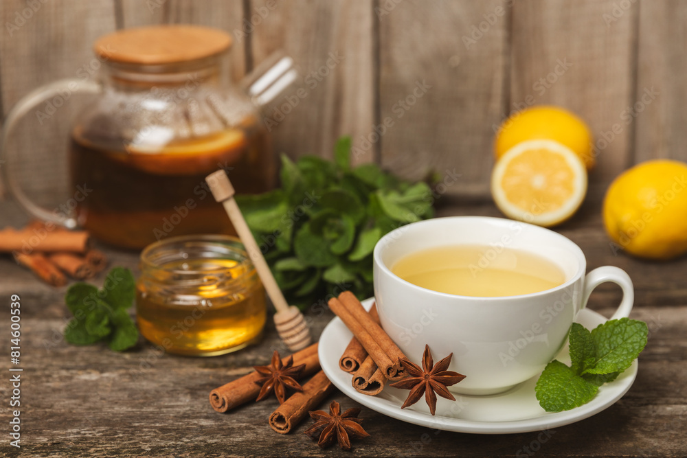 Fragrant hot tea with cinnamon stick and anise on a textured wooden background. A cup of hot tea with honey, lemon, mint and apples. Spicy tea with spices. Immunity tea. Health concept.Copy space. Fragrant hot tea with cinnamon stick and anise on a textured wooden background. A cup of hot tea with honey, lemon, mint and apples. Spicy tea with spices. Immunity tea. Health concept.Copy space.