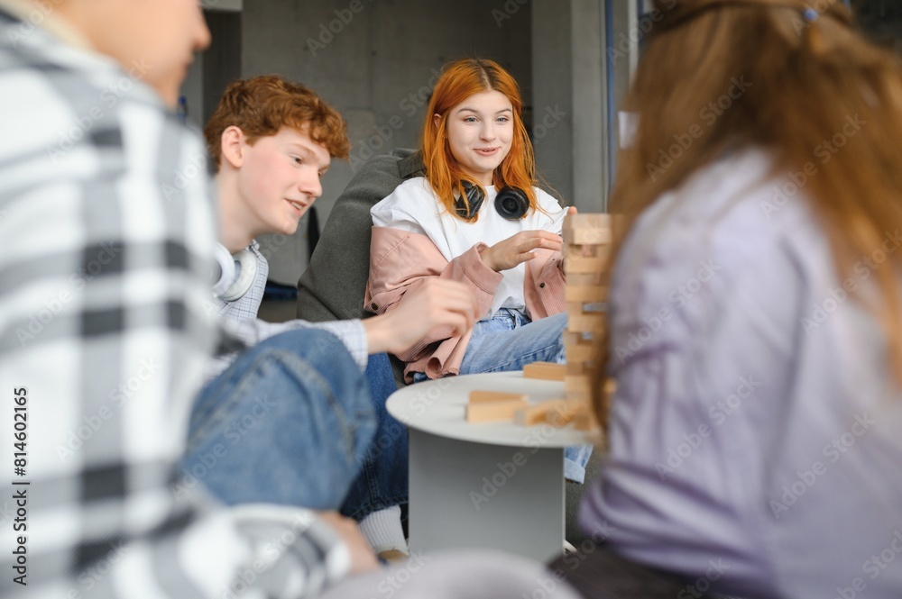 group of young friends playing board games together while sitting around table group of young friends playing board games together while sitting around table