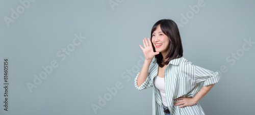 Profile view of a woman who loudly announces advertisements, news and information about discounts holding her hand near her mouth open. Lady exclaims near free space for text on green background.