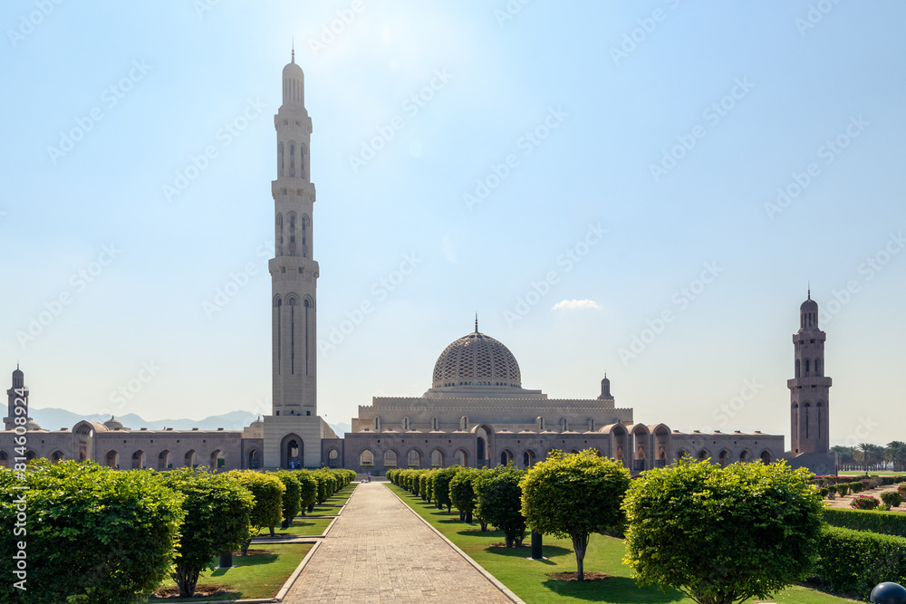 Naklejka premium A serene view of the iconic Sultan Qaboos Grand Mosque in Muscat, Oman, showcasing its intricate Islamic architecture and beautifully landscaped gardens.