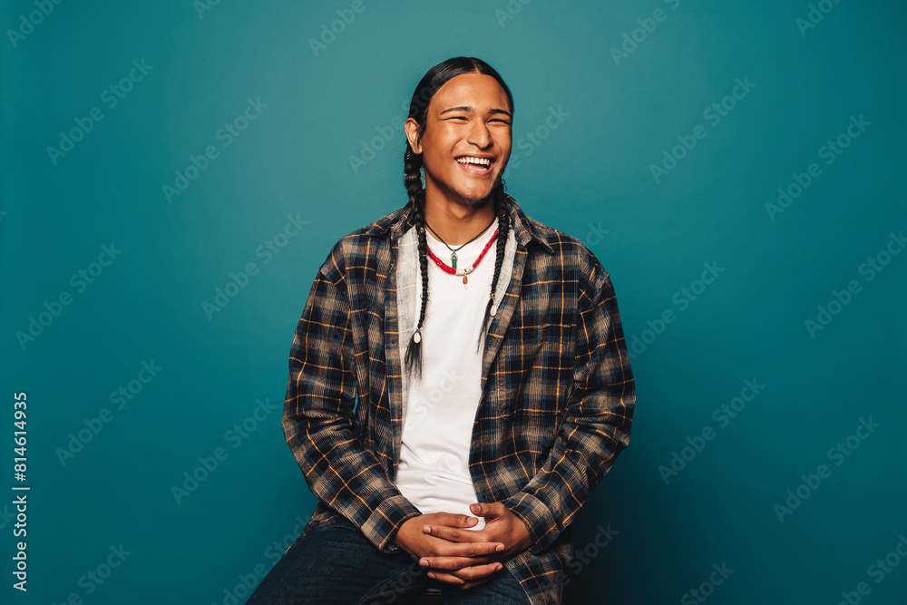 Happy young man with braided hair and ethnic jewelry on blue background Happy young man with braided hair and ethnic jewelry on blue background