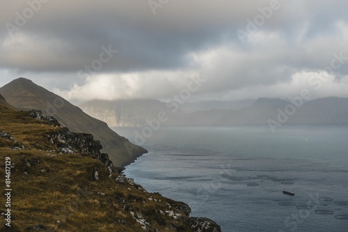 A body of water surrounded by mountains under a cloudy sky, Faroe Islands photo