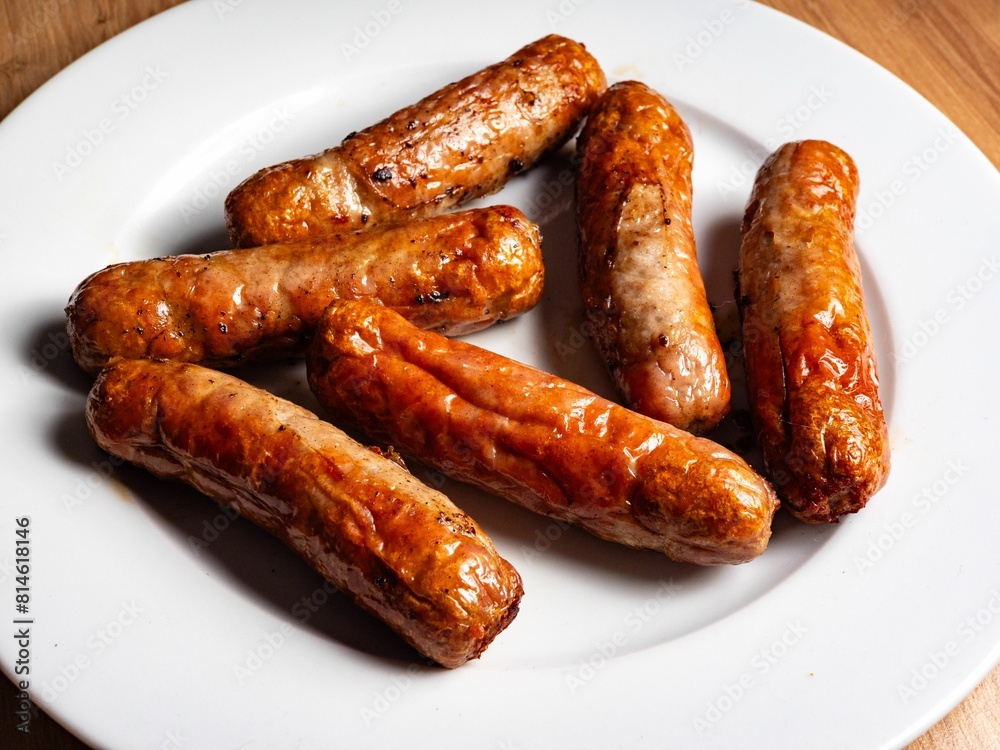 Closeup shot of a plate of grilled delicious sausages on a wooden table Closeup shot of a plate of grilled delicious sausages on a wooden table