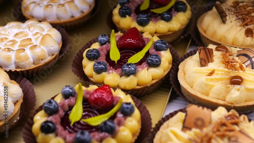 Close-up pastry tarts with different fillings neatly laid out display. Multi-colored fruit tarts with filling and impeccable decoration look tempting. Tart is work culinary art lovingly created master