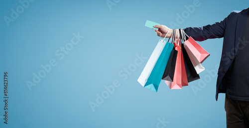 Valokuva Man holding multiple shopping bags on blue background