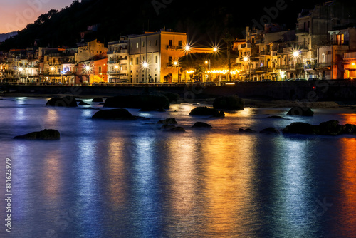 evening or night landscape of sea gulf with calm water and beautiful evening town highlighted with with lanterns and flashlights