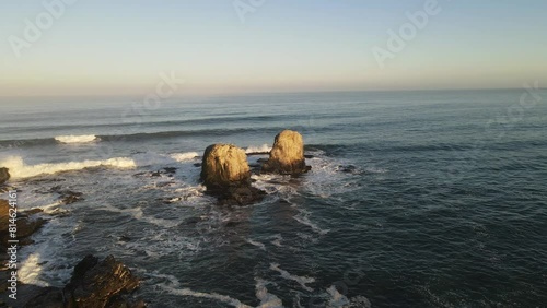 Drone footage of the Ocean waves crashing on the rocks of Punta de Lobos at sunset, Chile photo