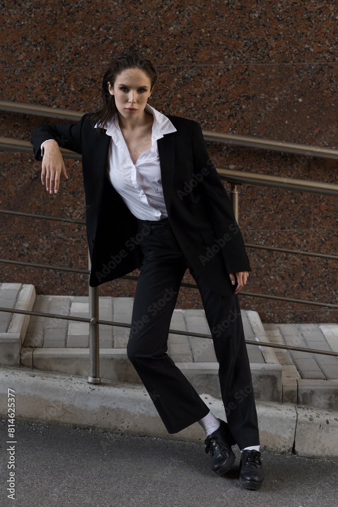 Attractive caucasian young woman in suit posing while walking outdoors on spring day. Luxurious, sexy and elegant lady looking at the camera. Beauty, Fashion, Style, Lifestyle.