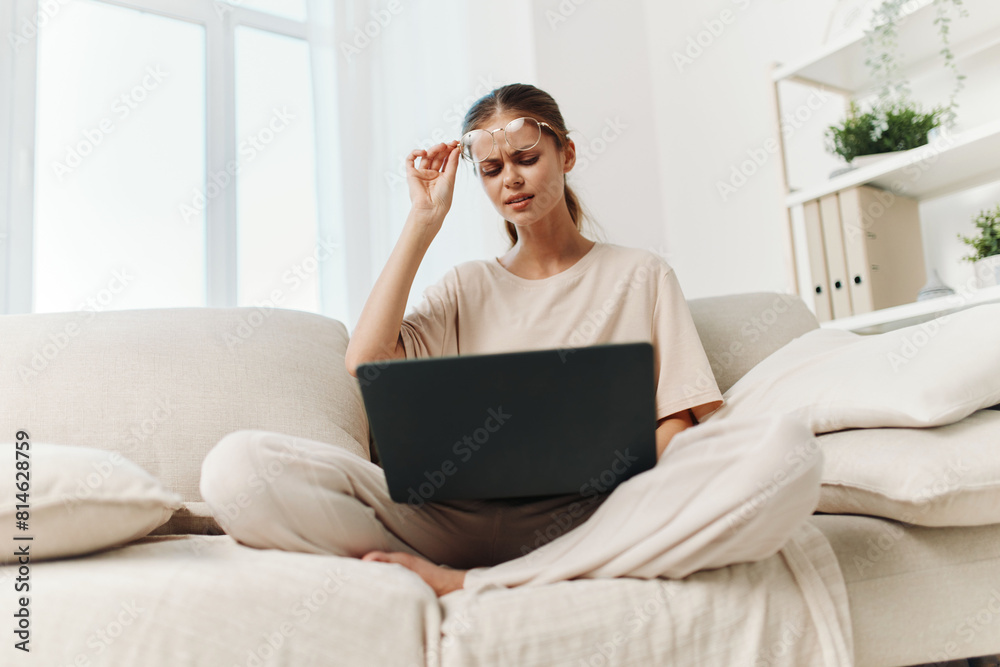 Smiling Woman Typing on Laptop at Home, Enjoying Freelance Job in Cozy Living Room Smiling Woman Typing on Laptop at Home, Enjoying Freelance Job in Cozy Living Room