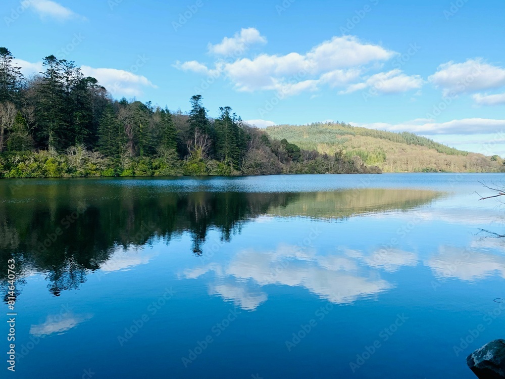 a beautiful lake surrounded by woods on a sunny day with blue sky and clouds a beautiful lake surrounded by woods on a sunny day with blue sky and clouds