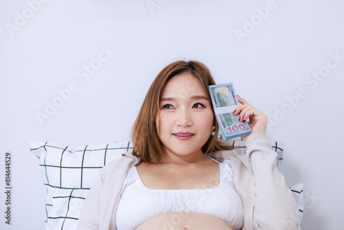 pregnant woman holds a lot of money in her hand. Monetary expenses for pregnancy and childbirth