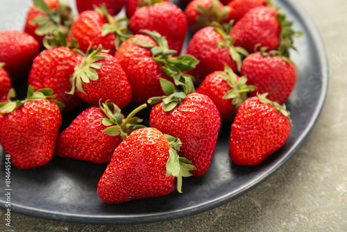 Top of view fresh strawberry in dark plate on grey concrete background.