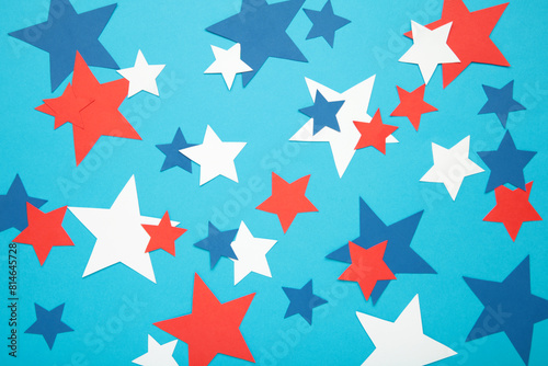 American independence day, celebration, patriotism and holidays concept - red, white and blue paper stars on blue background.