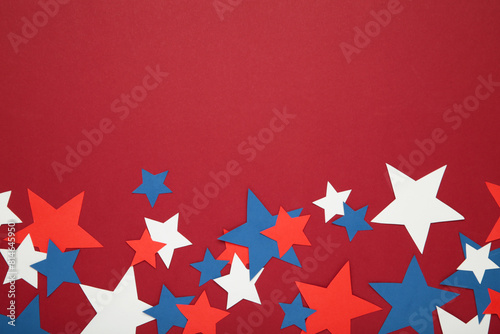 American independence day, celebration, patriotism and holidays concept - red, white and blue paper stars on red background.