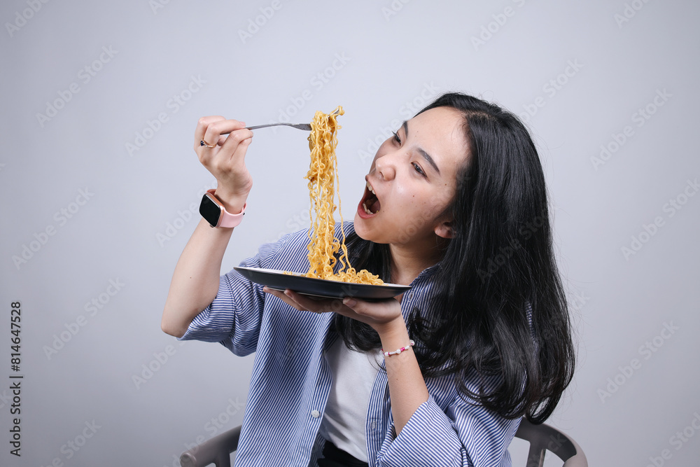 Potrait Of Young Asian Woman Pull The Noodles to Eat Isolated on Gray Background Potrait Of Young Asian Woman Pull The Noodles to Eat Isolated on Gray Background