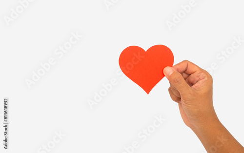 Close-up of hand holding a red heart symbol made from red paper against a white background.