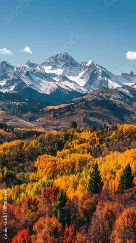 A majestic view of a mountain range during autumn  showcasing vibrant fall colors on the trees and foliage. The image captures the rugged peaks and valleys  with a clear blue sky overhead.