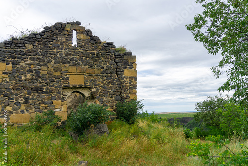 Ruins of an old stone church on the edge of a cliff. Bushes, green and yellow grass.  Samshvilde, Georgia photo