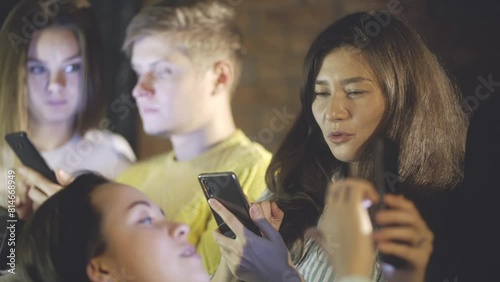 Close-up of young girl lying on knees of her friend and fliping social networks on mobile phone or smartphone. Friendship of millennial with modern technology or fabbing. Concept of teens home party, photo