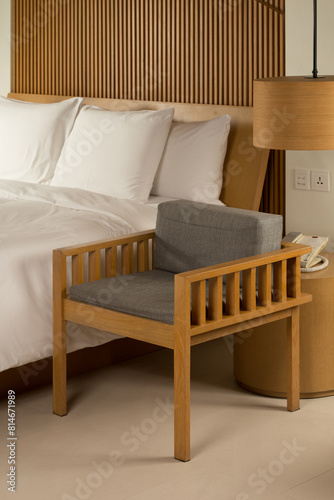 An elegant bedroom, featuring a wooden chair and a cozy bed, bathed in warm, inviting light.