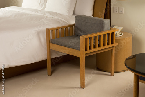 An elegant bedroom, featuring a wooden chair and a cozy bed, bathed in warm, inviting light.