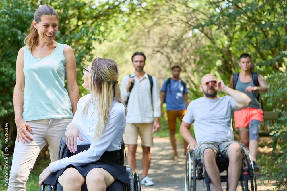 Group of friends enjoying a sunny day outdoor walk, including persons using wheelchairs and a woman with a prosthetic leg Group of friends enjoying a sunny day outdoor walk, including persons using wheelchairs and a woman with a prosthetic leg