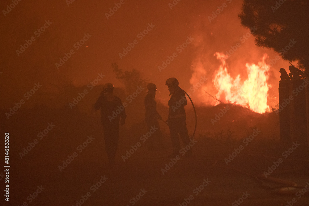 Fototapeta premium Firemen extinguishing the fire during night