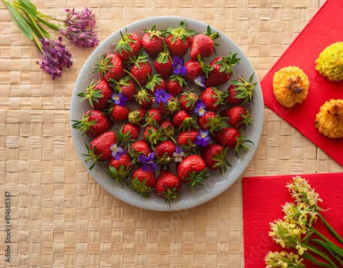 Plate with strawberries, forest spring flowers and cookies.