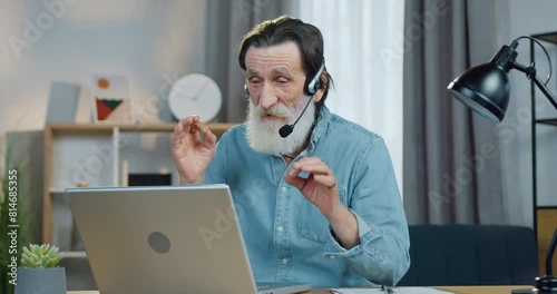 Attractive old man teacher holding online lessons with listeners or students from home. Distant education concept