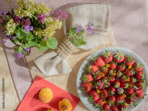 Spring forest flowers, strawberries and napkin on the table