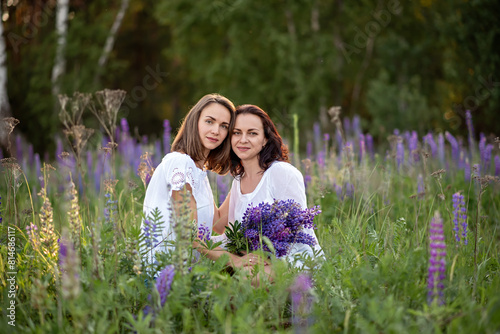 Two beautiful young sisters in a field of lupine flowers.