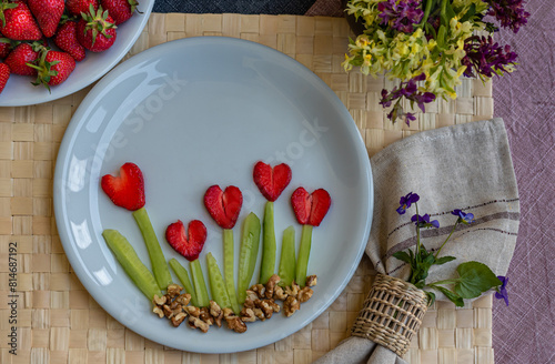 Dish with strawberries in the form of flowers in the shape of hearts, spring flowers on the table