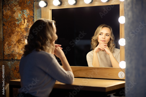 Portrait of young woman looking at her reflection in the mirror. photo