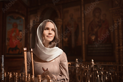 Young beautiful woman in the Orthodox Church lit candles in a candlestick