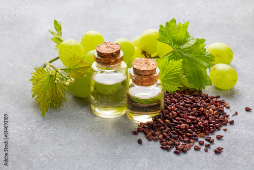 Grape seed oil in small bottle and bunch of grapes together.