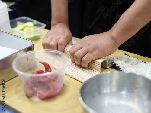 chef experto en cocina asiática elaborando rollo de sushi con sus manos photo