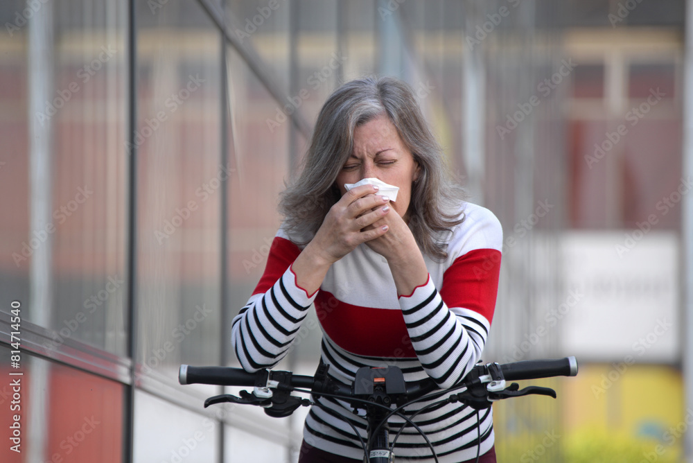 Fototapeta premium Senior woman has allergy, Woman sneezing in front of blooming