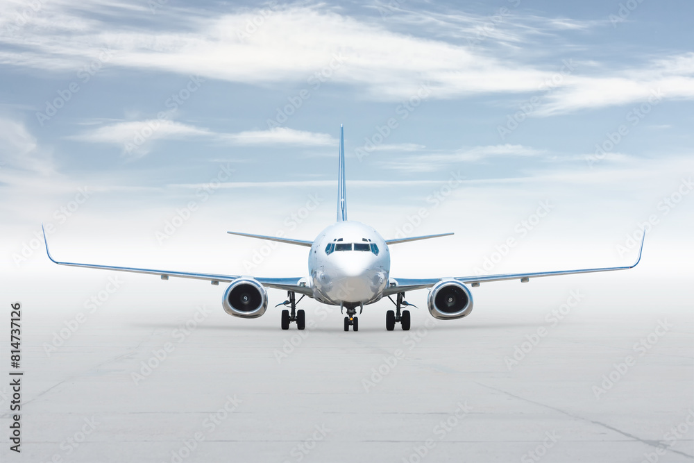 Front view of the white passenger jetliner isolated on bright background with sky Front view of the white passenger jetliner isolated on bright background with sky