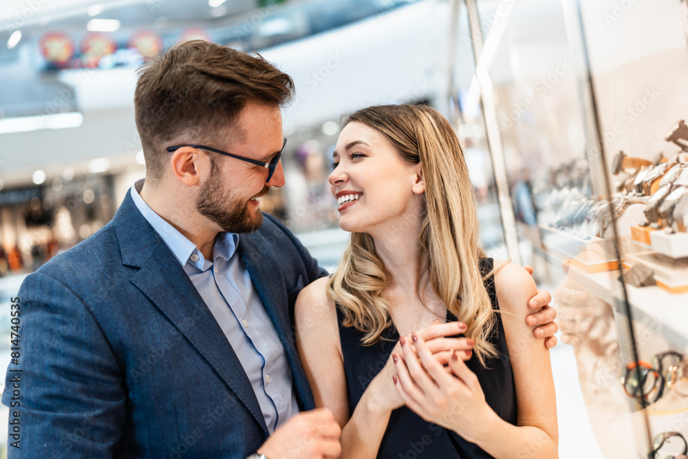 Beautiful couple enjoying in shopping at modern jewelry store. Men fashion and elegance concept. Beautiful couple enjoying in shopping at modern jewelry store. Men fashion and elegance concept.