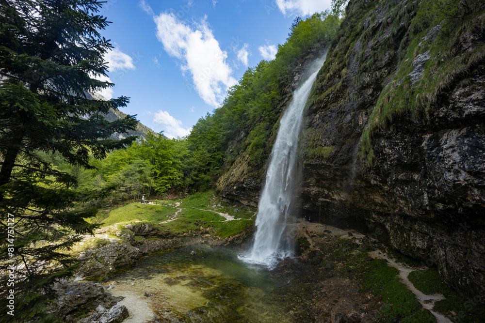 Fototapeta premium Fontanon of Goriuda, Udine. Wonderful waterfall that falls from a cliff. The force of the waterfall is a sight to behold. Hiking, trekking in the open area surrounded by woods. Summer holidays, peace.