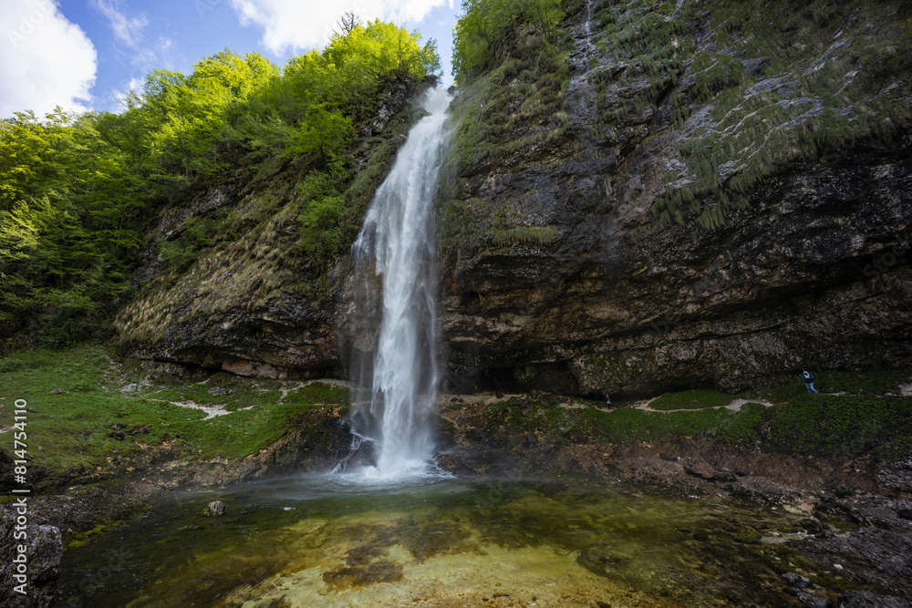 Fototapeta premium Fontanon of Goriuda, Udine. Wonderful waterfall that falls from a cliff. The force of the waterfall is a sight to behold. Hiking, trekking in the open area surrounded by woods. Summer holidays, peace.