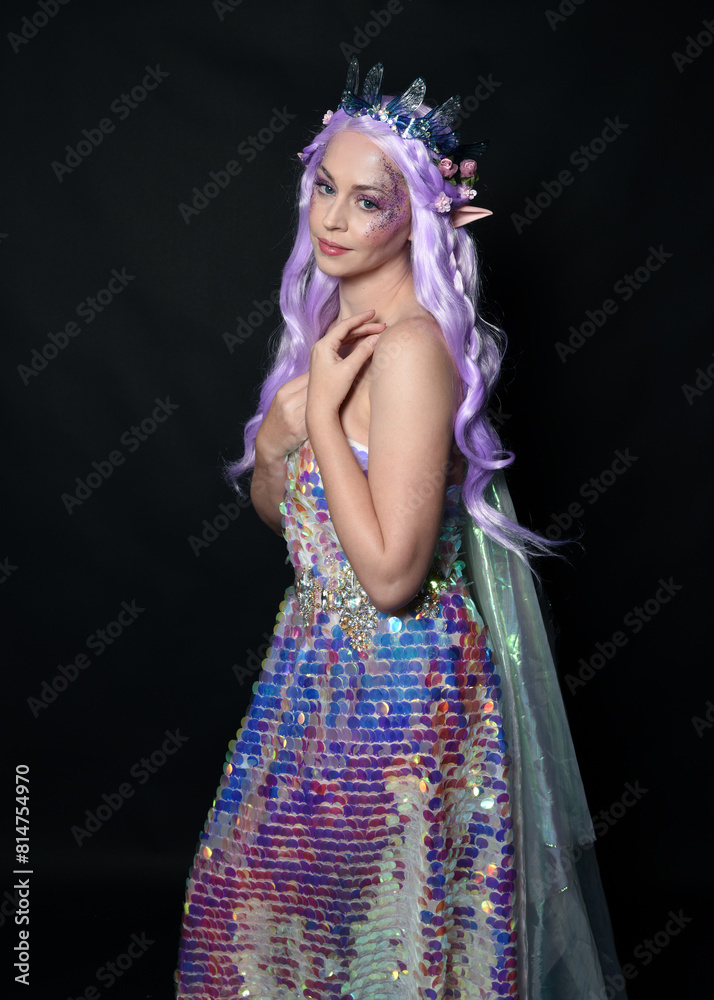 artistic portrait of beautiful female model with long purple hair and elf ears, wearing a fantasy fairy crown, wearing a rainbow glitter sequin ball gown. Standing in side profile, isolated on dark st artistic portrait of beautiful female model with long purple hair and elf ears, wearing a fantasy fairy crown, wearing a rainbow glitter sequin ball gown. Standing in side profile, isolated on dark st