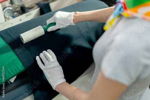 top shot close up professional dry cleaner young girl uses an adhesive roller to remove wool on a black jacket 