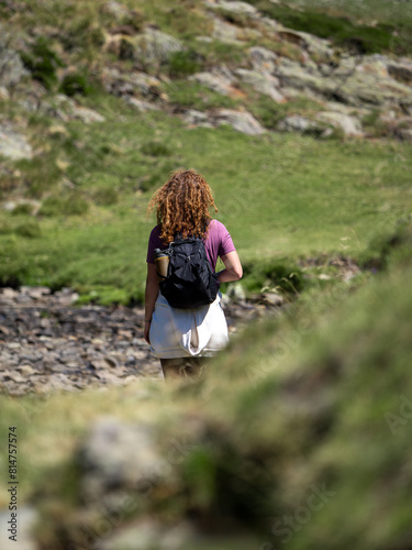Woman Hiking Through Rocky Mountain Terrain with Backpack and reusable water bottle photo