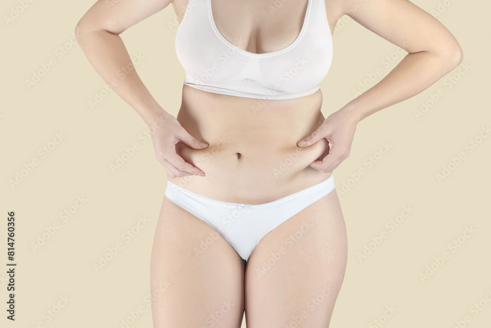 Woman has excess fat. Girl in underwear shows belly fat. She wants to lose weight nude yellow background