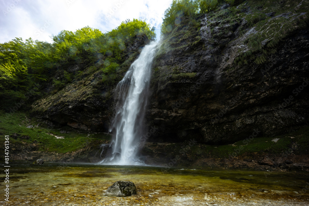 Obraz premium Fontanon of Goriuda, Udine. Wonderful waterfall that falls from a cliff. The force of the waterfall is a sight to behold. Hiking, trekking in the open area surrounded by woods. Summer holidays, peace.